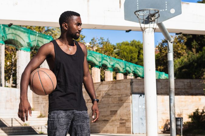 Serious Black man with basketball on sports ground