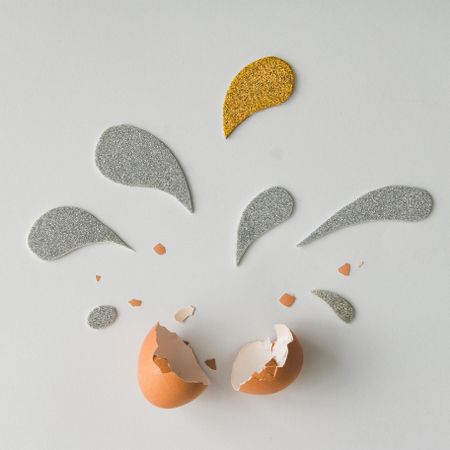 Egg shell with silver and golden glittering splashes on light background