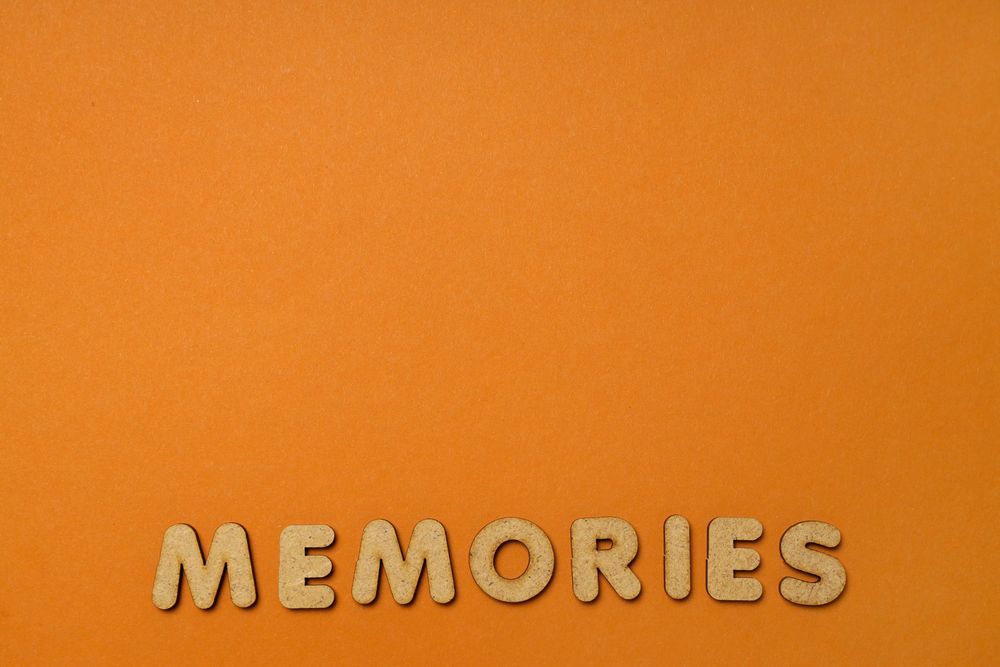 The word “Memories” written in cork on dusty orange background, copy space