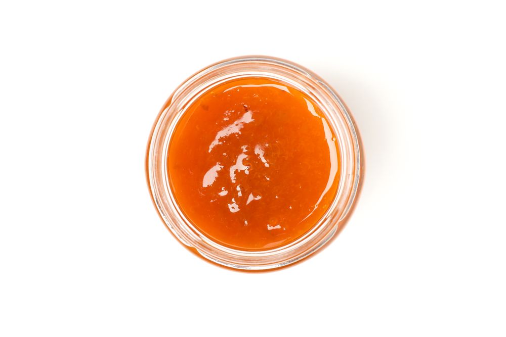 Glass jar with apricot jam isolated on blank background