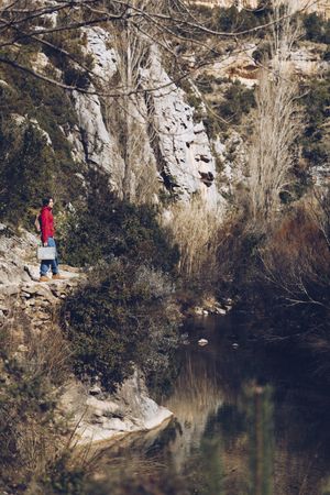 Traveling woman on lake in rocky cliffs