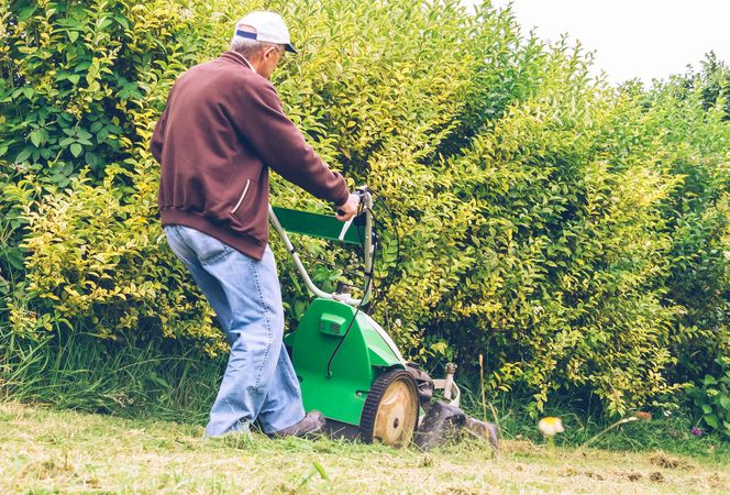 Mature man mowing the lawn with lawnmower