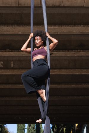 Slim woman doing yoga with aerial silks in city