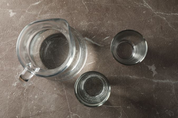 Top view of glasses of water and jug on grey marble table