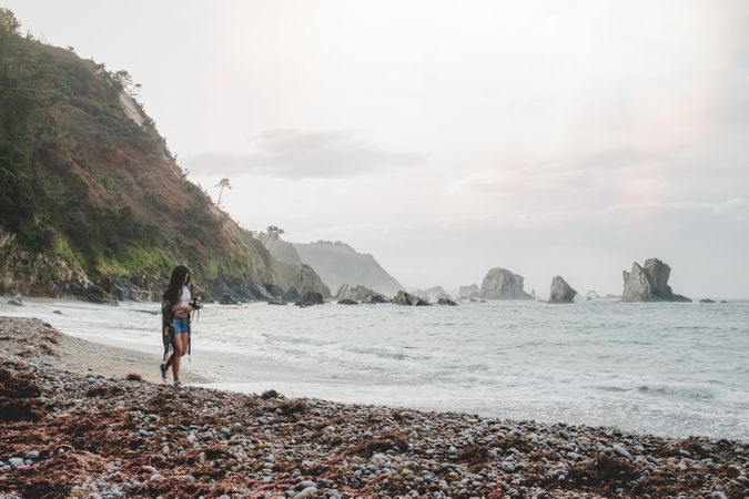 Woman with camera on shore near stones and water