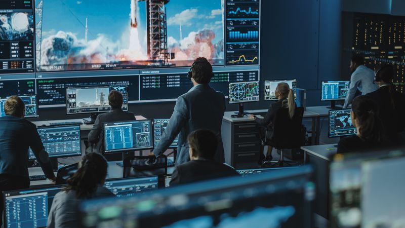 Technicians Analyze Real-time Data Across Multiple Displays in Dimly Lit Control Room.