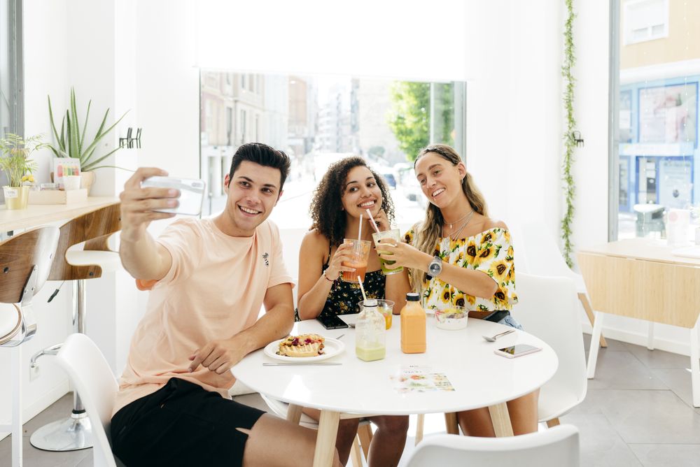 Man taking selfie of friends in cafe