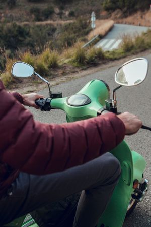 Man in warm jacket sitting on scooter holding wheel