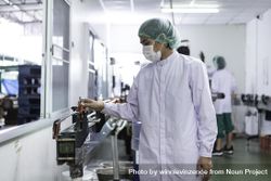 Male on production line of bottling plant in facemask and hairnet 42Gn1b