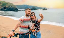 Male and female taking picture of themselves with their pet dog along the coast