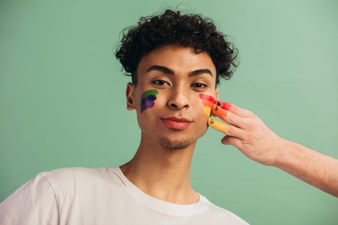 Hand painting rainbow color on a man's face