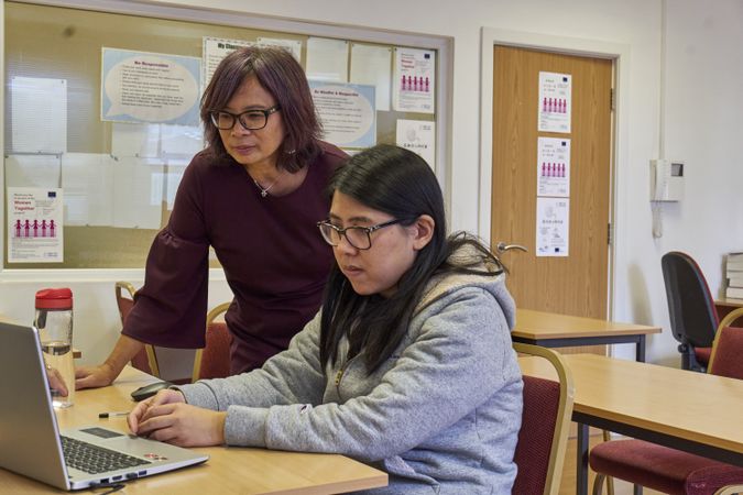 Older Asian woman teaching a student in classroom