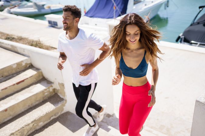 Man and woman exercising on stairs near waterfront