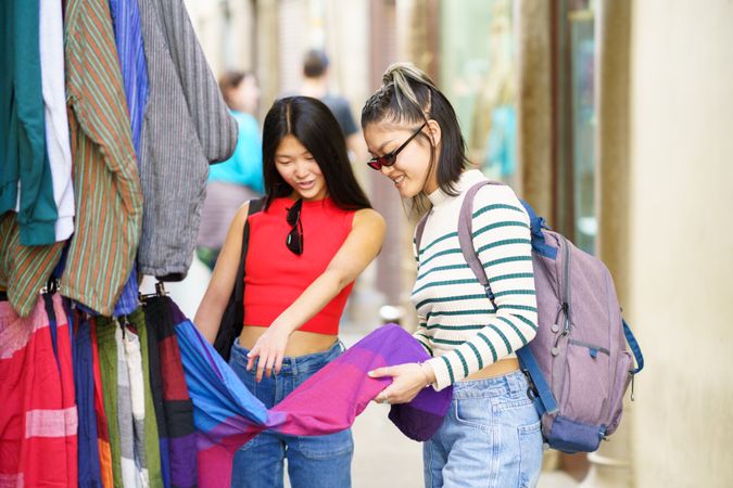 Asian female shopping choosing clothes in market of Granada