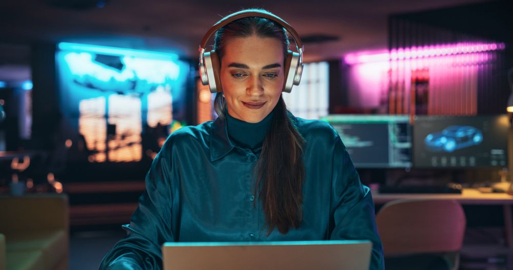 Young Project Manager with Headphones Working on Laptop Computer in Creative Office Environment.