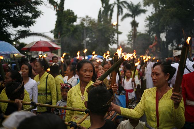 Group of Indonesian Hindu women with torches with lit flames marching during Nyepi day