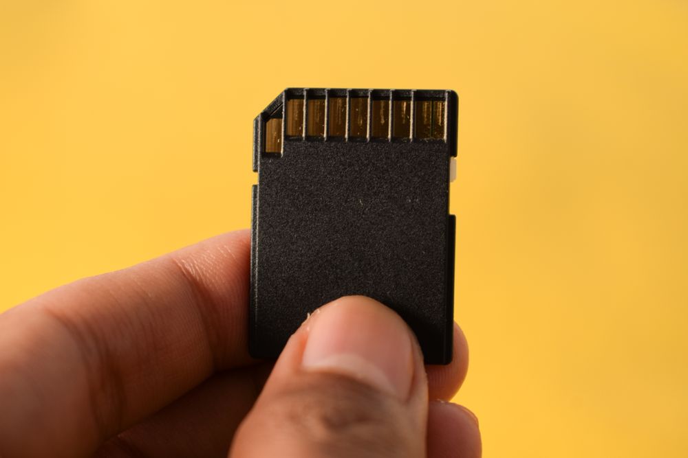 SD card in hand with yellow background and space for text