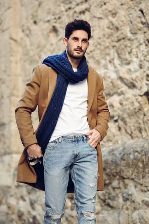 Suave man in jeans and winter coat walking outside