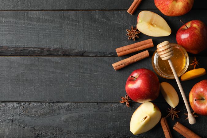 Autumnal apples and cinnamon sticks on dark wooden table with copy space