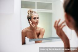 Female looking into the mirror and touching her face 4dPxL4