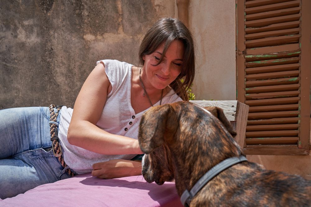 Smiling female lying on mattress and playing with pet