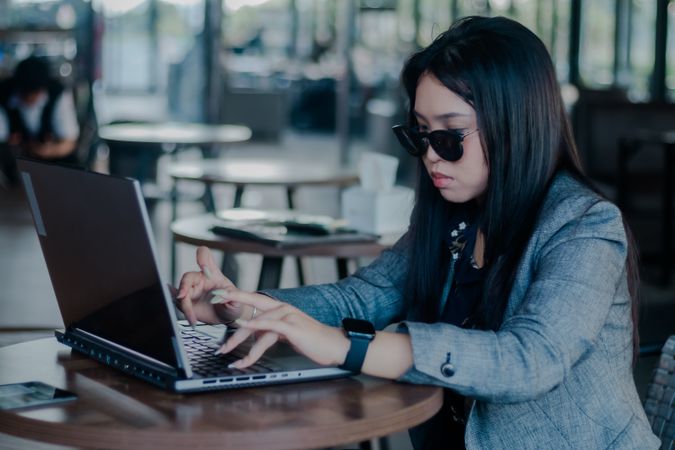 Focused professional typing on laptop in stylish cafetting