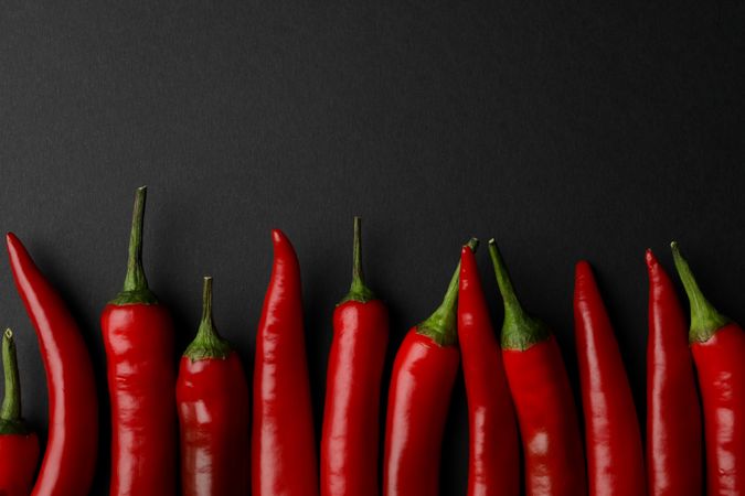 Chilli peppers on dark background, top view