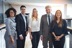 Portrait of a group of colleagues in business attire smiling at work