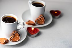 Two coffees with iced cookies and heart candles