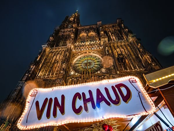 Hot wine "vin chaud" sign at Christmas market under gothic church in Alsace