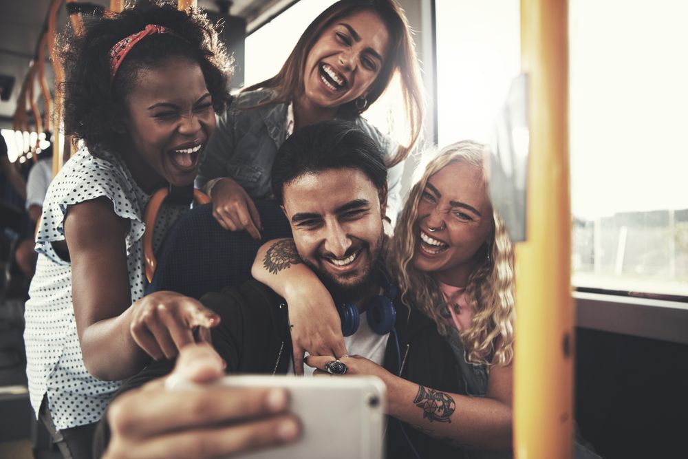 Multi-ethnic group of friends taking pictures on the bus together