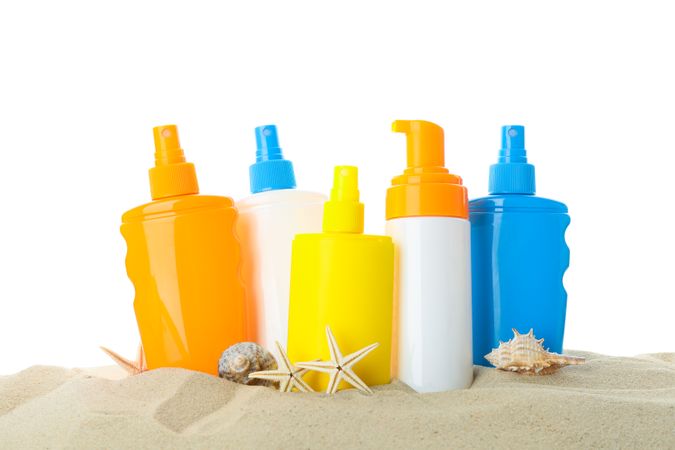 Sunscreens with starfish and seashells on clear sea sand. Summer vacation