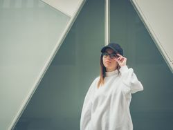 Young woman with glasses standing against wall