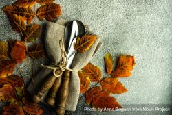 Autumnal table setting with bright yellow leaves on stone background with copy space 0yKgO4