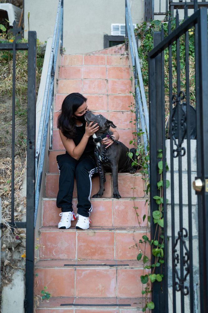 Woman with PPE mask kissing her dog before dog walk