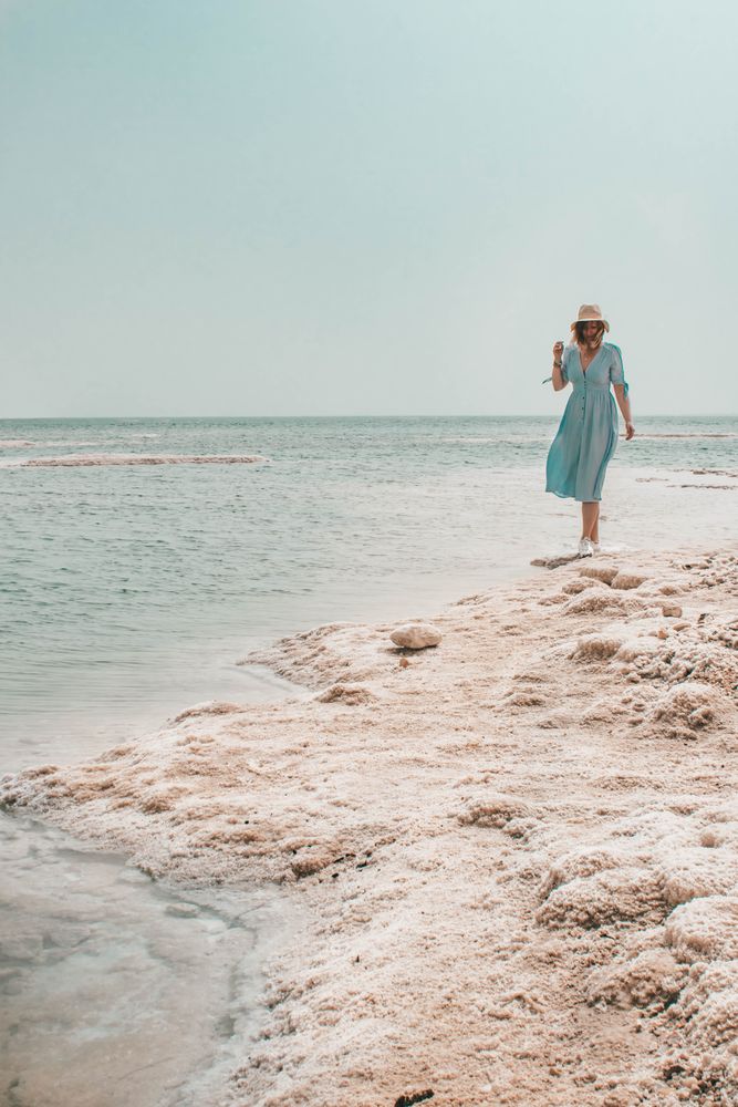 Woman in blue dress and a hat standing on seashore