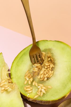 Sliced small melon on plate with spoon and fork