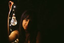 Thoughtful woman with burning lightbulb in darkness
