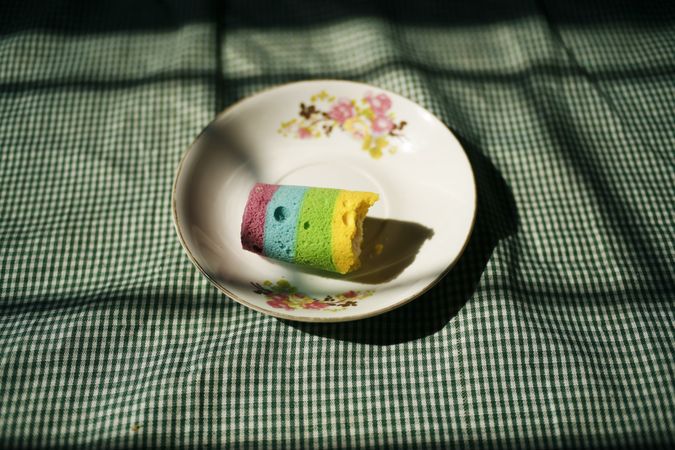 Bitten into multicolored cake on plate resting on table