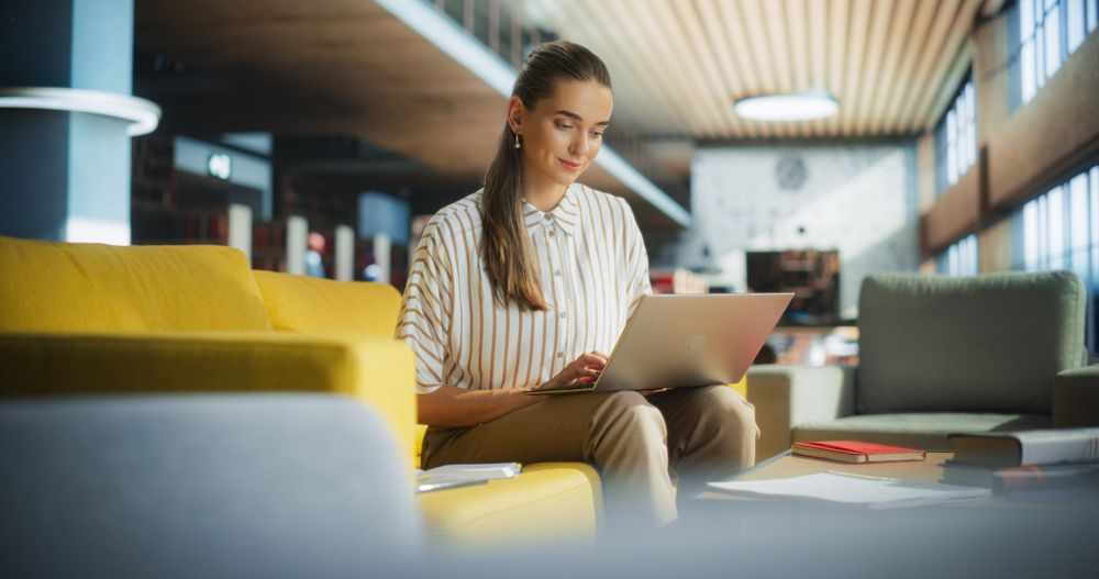 Smart College Student Using Laptop Computer to Study in a Public Library.