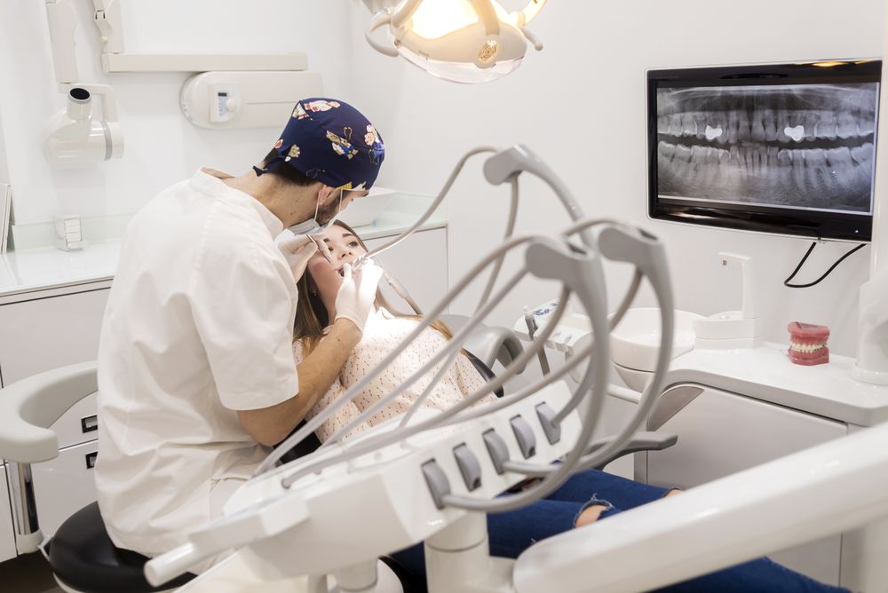 Masked male dentist working on mouth of teenage patient
