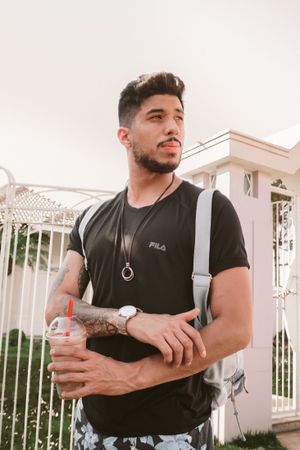 Man with backpack holding iced coffee