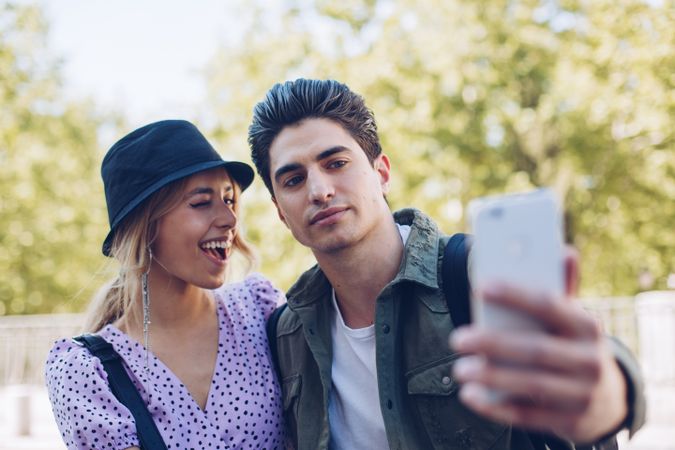 Happy young couple taking selfie in park