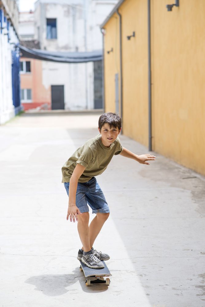 Front view of cheerful teen boy riding skateboard
