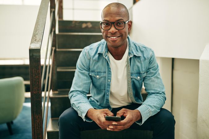 Portrait of man in jean jacket on stairwell with cellphone