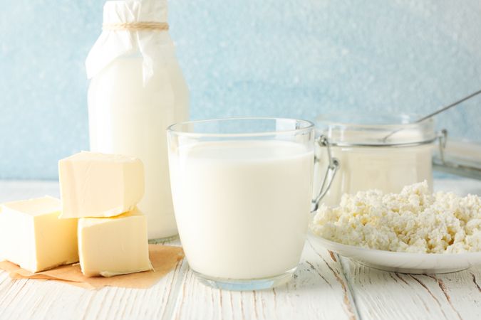 Different dairy products on wooden table against blue background, copy space
