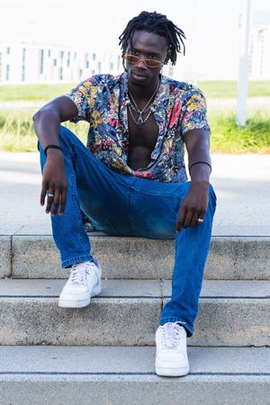 Stylish Black hipster man sitting on stairs in city