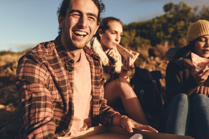 Group of friends on hiking trip eating pizza together