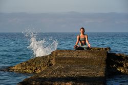 Woman in sportswear sitting on stone and meditating