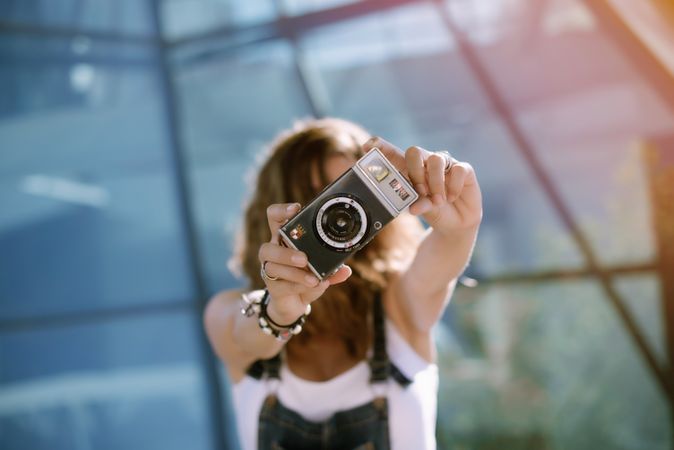 Creative woman taking photo on camera in sunny day